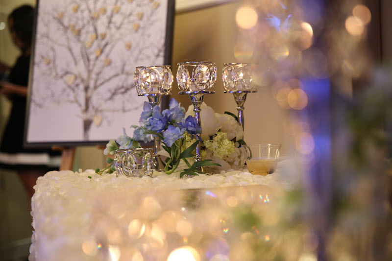 Crystal candle holders and blue floral centerpiece at a wedding reception at Asian Palace